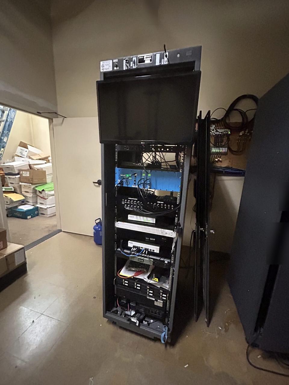 Onsite service photo showing equipment cabinet cabling and switch handoff with private labels omitted